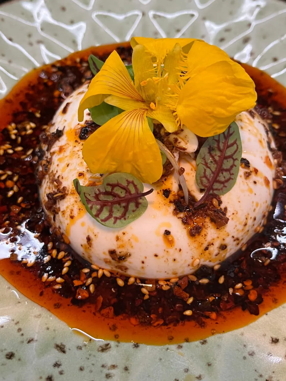 Burrata with chilli crisp, toasted sesame, sorrel and an edible flower
