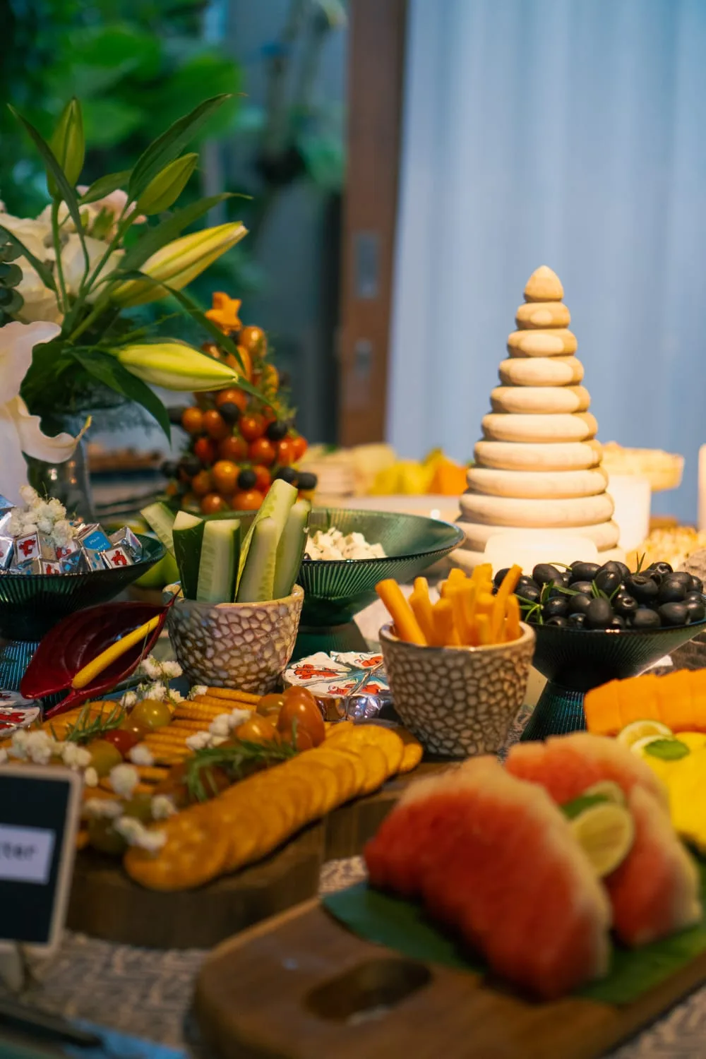 Villa canapé spread — cucumber batons, olives, cheese sticks, watermelon and lilies